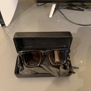 Chimi solglasögon - Snygga svarta solglasögon med breda bågar och fyrkantig form. Kommer med ett hårt fodral och en svart putsduk. Perfekta för att ge en cool vibe till din outfit.