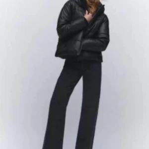 Svart pufferjacka - Säljer en svart pufferjacka med luva och dragkedja. Jackan är quiltad och har en oversized passform som ger en cool och avslappnad vibe. Perfekt för kalla dagar och enkel att styla till olika outfits.