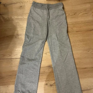 Grå mjukisbyxor från 157, storlek S - Grå mjukisbyxor från 157 i storlek S. Byxorna har rak passform, elastisk midja med snörning och är tillverkade i mjukt bomullsmaterial. Perfekta för chill dagar eller när du vill vara extra bekväm. Snygg enkel design utan mönster.