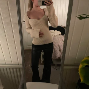 Beige ribbad stickad tröja - Säljer en beige stickad tröja med ribbad struktur och snygg sweetheart-urringning. Tröjan har lång ärm med lite utsvängda ärmslut och sitter figurnära. Perfekt att styla med både jeans och skinnbyxor för en trendig look.