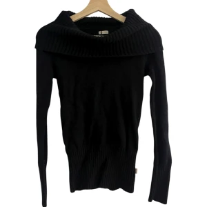 Svart stickad fold over tröja - Svart stickad tröja med bred, ribbad krage som kan bäras offshoulder. Tröjan har långärmad passform och ribbade muddar vid ärmslut och nederkant. 