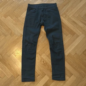 Levi's 512 mörkblå/mörkgröna jeans W31 L32 - Snygga Levi's 512 jeans med slim passform och klassisk femficksdesign. Jeansen har en modern, smal siluett och är tillverkade i mjukt jeansmaterial med stretch för extra komfort. Perfekta för dig som gillar stilrena och tidlösa plagg. Stl. W31/L32