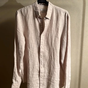 Ljusbeige linneskjorta från Cubus - Säljer en stilren ljusbeige skjorta i linne från Cubus. Skjortan har klassisk krage, knäppning framtill och långa ärmar. Perfekt för dig som gillar en avslappnad men ändå clean look.