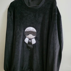 Svart sammetsset tracksuit FF - Snyggt svart sammetsset från FFmed ikoniskt broderat motiv framtill på både tröja och byxa. Tröjan har rund hals och byxan har snörning i midjan samt dragkedjor vid fickorna. Mjukt material och coola detaljer med nitar på motivet.