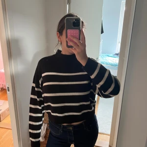 Svartvit randig croppad stickad tröja - Svart stickad tröja med vita horisontella ränder och croppad passform.  I bra skick, storlek M från H&M 🖤