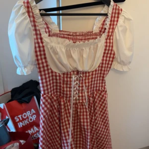 Oktoberfest klänning - Superfin rödvit rutig klänning med puffiga korta ärmar och snörning framtill. Perfekt om du ska på oktoberfest eller kanske till halloween!