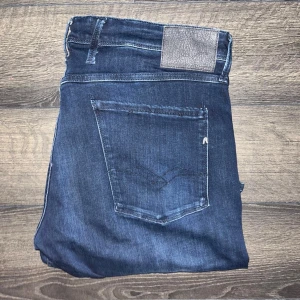 Replay Anbass jeans - Säljer ett par Replay Anbass jeans i mörkblå tvätt. Klassisk femficksmodell med raka ben och snygga detaljer på bakfickorna. Jeansen är tillverkade i stretchig bomullsdenim för skön passform och har en diskret Replay-logga på bakfickan. Midja 48cm, längd 111cm. JAG SKICKAR INGA FLER BILDER PÅ NÄR JAG BÄR PLAGGET:) s2