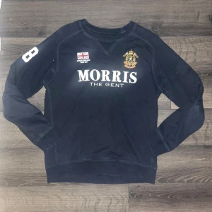Morris  - Snygg mörkblå sweatshirt från Morris Gents med tryck på bröstet och ärmen. Tröjan har rund hals, långa ärmar och broderad logga samt brittisk flagga framtill. Perfekt för en stilren och sportig look. Bredd mellan armhålorna 50cm, längd 67cm. JAG SKICKAR INGA FLER BILDER NÄR JAG BÄR PLAGGET PÅ:) s2