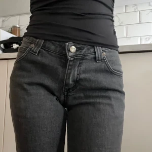 Mörkgrå Lee jeans med rak passform - Säljer ett par mörkgrå jeans från Lee med klassisk femficksdesign och raka ben.