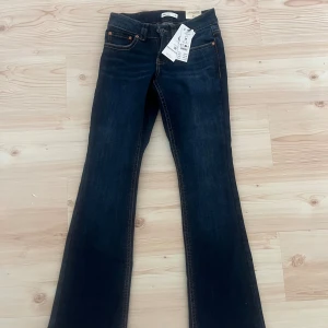 Y2K low bootcut jeans blå Gina Tricot - Mörkblå Y2K-inspirerade bootcut jeans från Gina Tricot i modell 'perfect jeans'. Klassisk femficksdesign, låg midja och snygga kontrastsömmar. Jeansen har utsvängda ben och coola bakfickor med lock. Perfekta för dig som gillar retrovibbar. Endast provade på och passade inte därför säljer jag mycket billigare. Ni kan ge pris förslag!