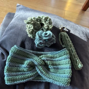 Stickat grönt pannband med twist - Handgjort stickat diadem i gröna och blå toner med snygg twist framtill. Diademet har bred form och ribbad struktur, perfekt för att ge din look en chill vibe. Materialet är mjukt och skönt, och färgerna går i en harmonisk mix av ljusgrönt och blågrönt. 2 hårsnoddar samt ett nyckelband!