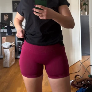 Vinröda seamless shorts från Gymshark - Säljer ett par vinröda seamless shorts från Relode. Helt nya, endast testade hemma men prislapp borta. För små för mig tycker jag. Men bra på en med samma str som mig om man gillar Tajt.De är lågmidjade, tighta och har en ribbad midja som sitter skönt. Perfekta för träning eller gymmet. Materialet är stretchigt och följsamt, vilket ger en snygg passform.