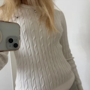 Vit kabelstickad tröja från GANT - Supersnygg kabelstickad tröja från GANT i färgen eggshell. Tröjan har rund hals, lång ärm och diskret broderad logga på bröstet. Tillverkad i mjuk bomull och passar perfekt till jeans eller kjol för en clean och klassisk look. Passar även xs  - pris går att diskuteras❣️Skriv vid frågor!