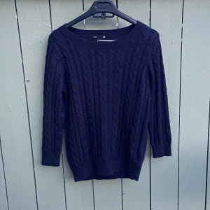 Mörkblå stickad tröja från H&M - Säljer en mörkblå stickad tröja från H&M Basic i storlek S. Tröjan har ett klassiskt kabelstickat mönster framtill och på ärmarna, rund halsringning och ribbade muddar. Perfekt för kyliga dagar och enkel att matcha med jeans eller kjol.mycket bra skick använd 1 gång.