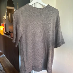 Beige/grå stickad tröja med kort ärm - stickad tröja med korta ärmar och ribbade detaljer vid hals, ärmslut och nederkant. Okänt märke 