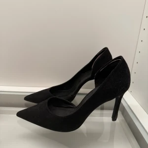 Svarta pumps från MNG med spetsig tå - Svarta pumps från MNG i mocka-look med elegant spetsig tå och hög klack. Klassisk och stilren design som passar perfekt till en dressad outfit. Snygg siluett och tidlös färg som funkar till det mesta.  Använd fåtal gånger men har lite skada på klacken men inget man lägger märke från distans🩷