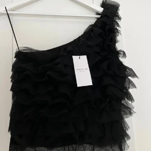Svart volangig oneshoulder topp Stockh LM - Supersnygg svart oneshoulder volang topp från Stockh LM Studio. Är i storlek M. Är aldrig använd och har prislappen kvar. Nypris är 500. Supersnygg till hösten, kan även användas till nyår. Ställ gärna frågor!🩷
