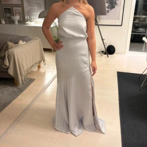 Balklänning  - Så vacker silverfärgad balklänning med slits vid ena benet, från CHANCERY. Storlek S. Passar personer som vanligtvis har XS-S💕  Klänningen har endast använts vid ett tillfälle, den är som ny🌟 Hör av dig om du har någon fundering!🫶🏽