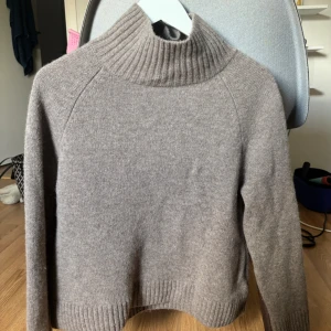 Beige polotröja från Wera - Mysig beige polotröja från Wera med ribbad hög krage och muddar. Tröjan är stickad och har lång ärm, perfekt för kyliga dagar. Enkel och stilren design som funkar till allt. Nypriset är 800kr och den är använd 2-3 gånger