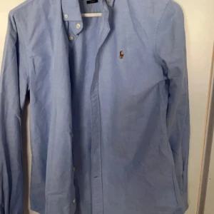Blå skjorta från Ralph Lauren - Säljer en Ralph lauren skjorta. Det är en tjej skjorta men sitter nästan precis som en vanlig fast i en storlek mindre. Denna är i storlek S så om du har typ xs/s bör den passa. 9,5/10 skick.
