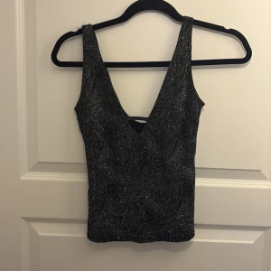 Glittrig topp  - Glittrig topp med v-ringning och cool detalj! Köpt på sellpy men från hm! Använd enstaka gång men bra skick!