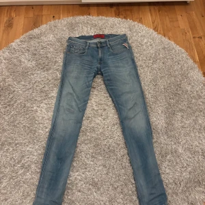 Replay Anbass ljusblå jeans, stl 30 - Snygga ljusblå Replay Anbass jeans med klassisk femficksdesign och smal passform. Jeansen har en modern tvätt, diskreta slitningar och är tillverkade i mjukt denimtyg. Perfekt för dig som gillar en stilren och avslappnad look.