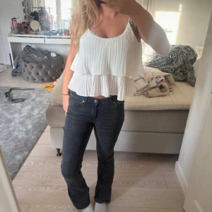 Vit plisserad linnetopp med volanger - Säljer en superfin vit linnetopp med plisserat tyg och dubbla volanger. Toppen är ärmlös med smala axelband och har en luftig, croppad passform som ger en fräsch och somrig vibe. Perfekt att styla med jeans eller kjol för en chill look.