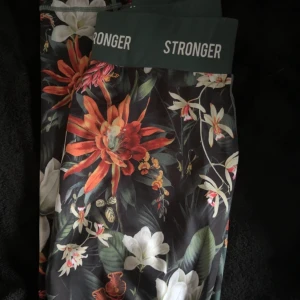 Blommiga leggings från Stronger - Träningsbyxor från Stronger med blommönster. Litet minimasliskt lagat hål på höger knä