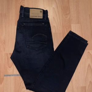 Svarta skinny jeans från G-Star RAW - Säljer ett par svarta skinny jeans från G-Star RAW med klassisk femficksdesign och dragkedja. Jeansen har en mörk tvätt, smal passform och är tillverkade i stretchigt bomullsmaterial för extra komfort. Perfekta för dig som gillar en clean och stilren look.