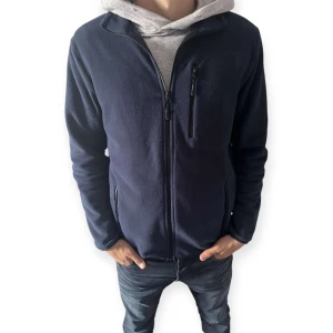 Mörkblå fleecejacka med dragkedja - Mysig mörkblå fleecejacka med hel dragkedja framtill och tre praktiska fickor med dragkedja. Jackan har en enkel och stilren design, perfekt för lager-på-lager och chill dagar. Normal passform och långärmad modell. (Modellen är 178 cm)