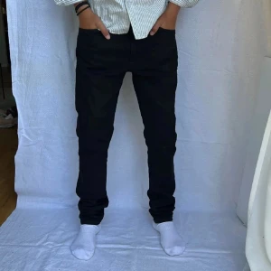 Svarta slim jeansbyxor - Svarta jeansbyxor med slim passform och klassisk rak design. Snygga och stilrena, perfekta för dig som gillar en enkel men modern look. Byxorna har normal midja och är tillverkade i ett stretchigt jeanstyg för extra komfort.