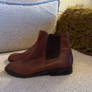 Boots i skinn - Snygga bruna chelsea boots med rund tå och platt sula. Bootsens ovandel är i mjukt skinn och har elastiska paneler på sidorna för enkel på- och avtagning. Perfekt för dig som gillar klassisk stil med en modern touch.