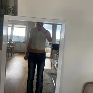 Vit croppad kofta med guldfärgade knappar - Supersöt vit croppad kofta från Gina Tricot med guldfärgade knappar och två dekorativa fickor framtill. Koftan har korta ärmar och är stickad i mjukt material som känns skönt mot huden. Perfekt för dig som gillar trendiga och stilrena plagg.