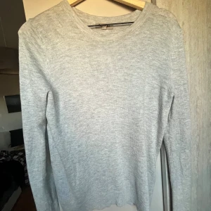 Ljusgrå stickad tröja Basic You S - En enkel och stilren ljusgrå stickad tröja från Basic You i storlek S. Tröjan har rund halsringning och långa ärmar, perfekt för lager-på-lager. Mjuk och skön känsla som passar till många outfits.
