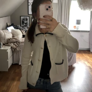 Vit kofta från Molly & Stitch med guldknappar - Superfin vit kofta från Molly & Stitch med snygga guldknappar och svarta detaljer vid krage och fickor. Rengör tröjan är såååå himla fin tycker bara den ej passar mig! Använd 2 gånger 🤍🤍WOW