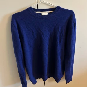 Blå stickad tröja från Van Gils - En klassisk blå stickad tröja från Van Gils med rund halsringning och långa ärmar. Tröjan har en enkel och stilren design, perfekt att matcha med jeans eller chinos. Mjuk och skön att bära under kyligare dagar.