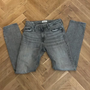 Gråa Jeans - Säljer dessa jättesnyggga Jens från Jack & Jones i färgen grå. Jeansen är i regular fit. W31(38cmk) och L34(104cm). Nypris: 600kr. Modellen är 190cm. Hör av er vid frågor!✌️