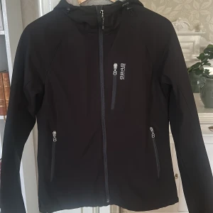 Svart friluftsjacka 8848 Altitude  - Svart friluftsjacka från 8848 Altitude med huva, hel dragkedja och tre fickor med dragkedja framtill. Jackan har ett fleecefoder på insidan. I väldigt fint skick trots år på nacken.