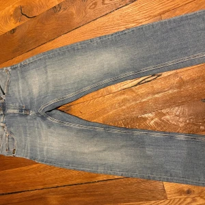 Ljusblå jeans Tiger of Sweden 28/30 - Snygga ljusblå jeans från Tiger of Sweden i modellen Evolve. Klassisk femficksdesign, slim straight design och diskreta slitningar för en avslappnad look. Jeansen är tillverkade i bomull och har en patch med logga bak på linningen.