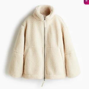 Beige teddyjacka med dragkedja - Mysig beige teddyjacka med hög krage och två stora fickor framtill. Jackan har en rak passform och stängs med dragkedja. Perfekt för kyliga dagar när du vill vara både varm och snygg. Säljs pga för korta ärmar för mig tyvärr. 
