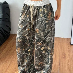 Baggy cargopants med camouflage - Baggy cargopants med camouflage-mönster i gröna, bruna och beige toner. Byxorna har resår och snörning i midjan för skön passform. Perfekta för en avslappnad streetstil.
