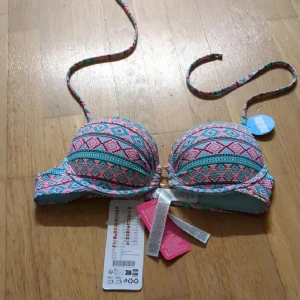 Bikinitopp - Snygg bikiniöverdel med färgstarkt geometriskt mönster i rosa, blått och turkost. Bikinin har vadderade kupor och smala axelband som knyts i nacken. Perfekt för strandhäng och poolparty!