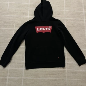 Svart hoodie från Levi's med logga - Svart hoodie från Levi's med stor röd och vit logga på bröstet. Använd ett par/flera gånger!💕