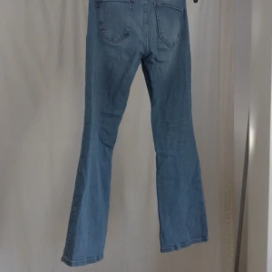 Ljusblå bootcut jeans - Säljer ett par ljusblå jeans med klassisk bootcut-modell. Jeansen har fem fickor, normal midja och är tillverkade i mjukt denimtyg. Perfekta för dig som gillar en retroinspirerad look med utsvängda ben. S short