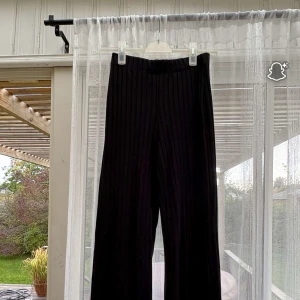 Svarta ribbade byxor från NA-KD - Svarta ribbade byxor från NA-KD i storlek S. Byxorna har en relaxed fit med vida ben och elastisk midja för extra komfort. Perfekta för en chill och stilren look, tillverkade i mjukt material som känns skönt mot huden.