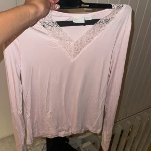 Ljusrosa långärmad topp med spets Gina Tricot - Supersöt ljusrosa långärmad topp från Gina Tricot med v-ringning och fina spetsdetaljer runt halsen. Mjuk och skön, perfekt att styla med jeans eller kjol. Enkel men ändå romantisk vibe.(köpt för någon månad sen men har inte kommit till användning):)