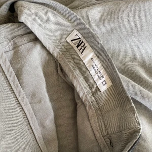 Ljusgrå chinos från Zara - Snygga ljusgrå chinos från Zara med jättefin passform och ett litet ”fakebälte” som är elastiskt. Jättesmidigt och snyggt. Säljes endast då de är för små för min pojkväns lillebror. Passar någon som är ca 185 cm❣️❣️❣️