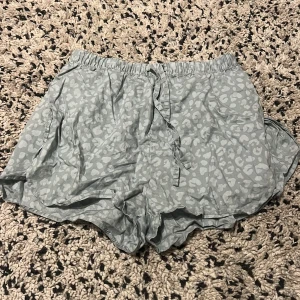 Ljusgröna leopardmönstrade shorts med snörning - Snygga ljusgråa shorts med diskret leopardmönster och bekväm resår i midjan. De har snörning framtill för extra passform och är perfekta för varma dagar. Lätta och luftiga, passar till chill eller när du vill sticka ut lite extra.