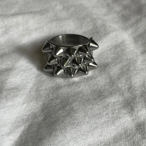 Edblad Silvrig ring med nitar -  Cool och chunky ring i silverfärgad metall från Edblad. med tre rader av spetsiga nitar runt hela framsidan. Perfekt för dig som gillar Stockholmstil. Storlek M (17.5 mm) Ny utan prislapp. Nypris 399 säljer för 330