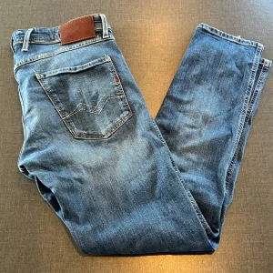  Replay Anbass jeans  - Snygga blå Replay Anbass jeans med klassisk femficksdesign och coola slitningar. Jeansen har normal midja och är gjorda i mjukt denimtyg som sitter skönt hela dagen. Perfekta för dig som gillar en stilren och modern look. Priset går såklart att diskutera 